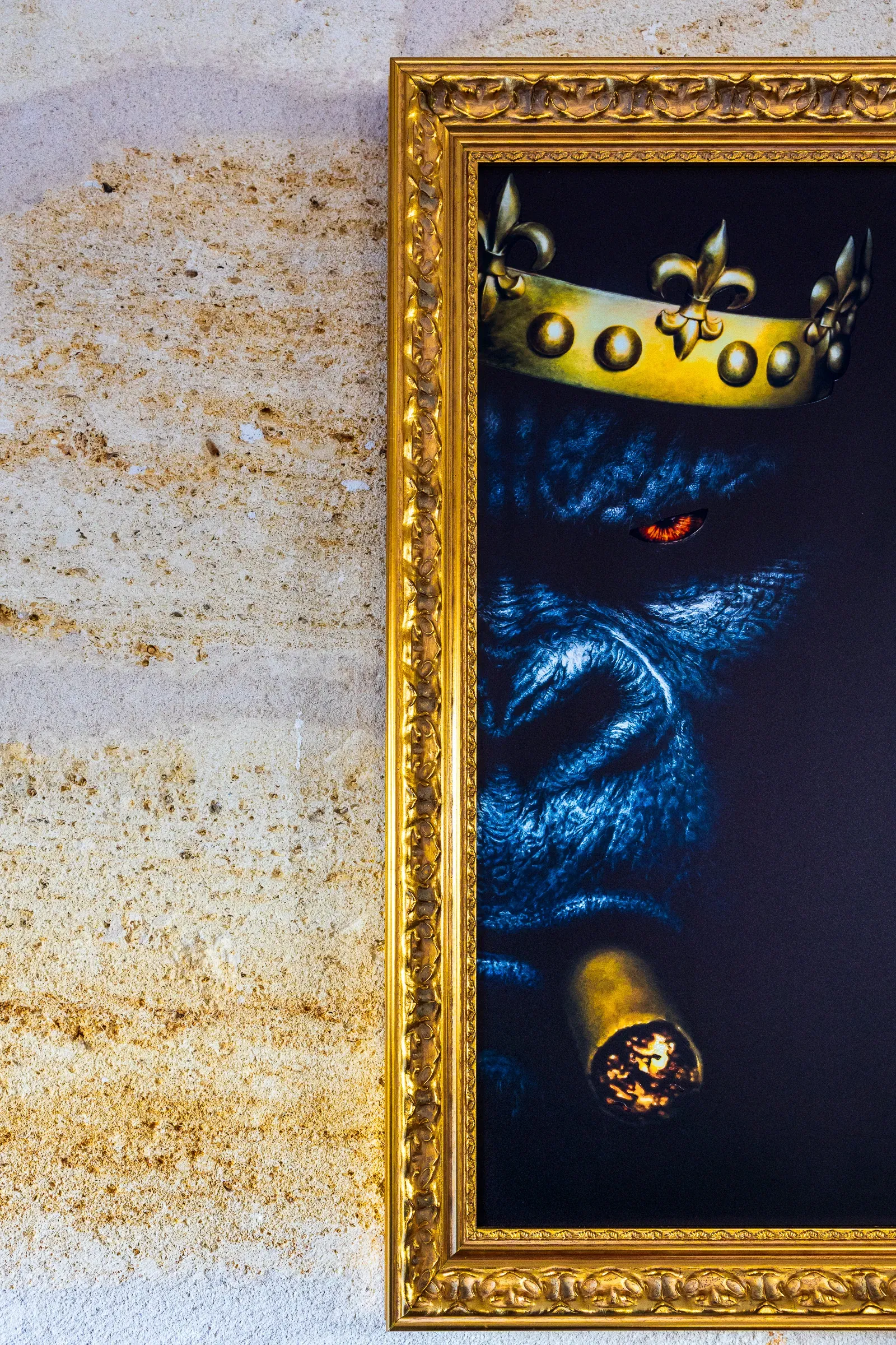 A crowned gorilla portrait in a gold ornate frame hanging on a weathered limestone wall, Bordeaux