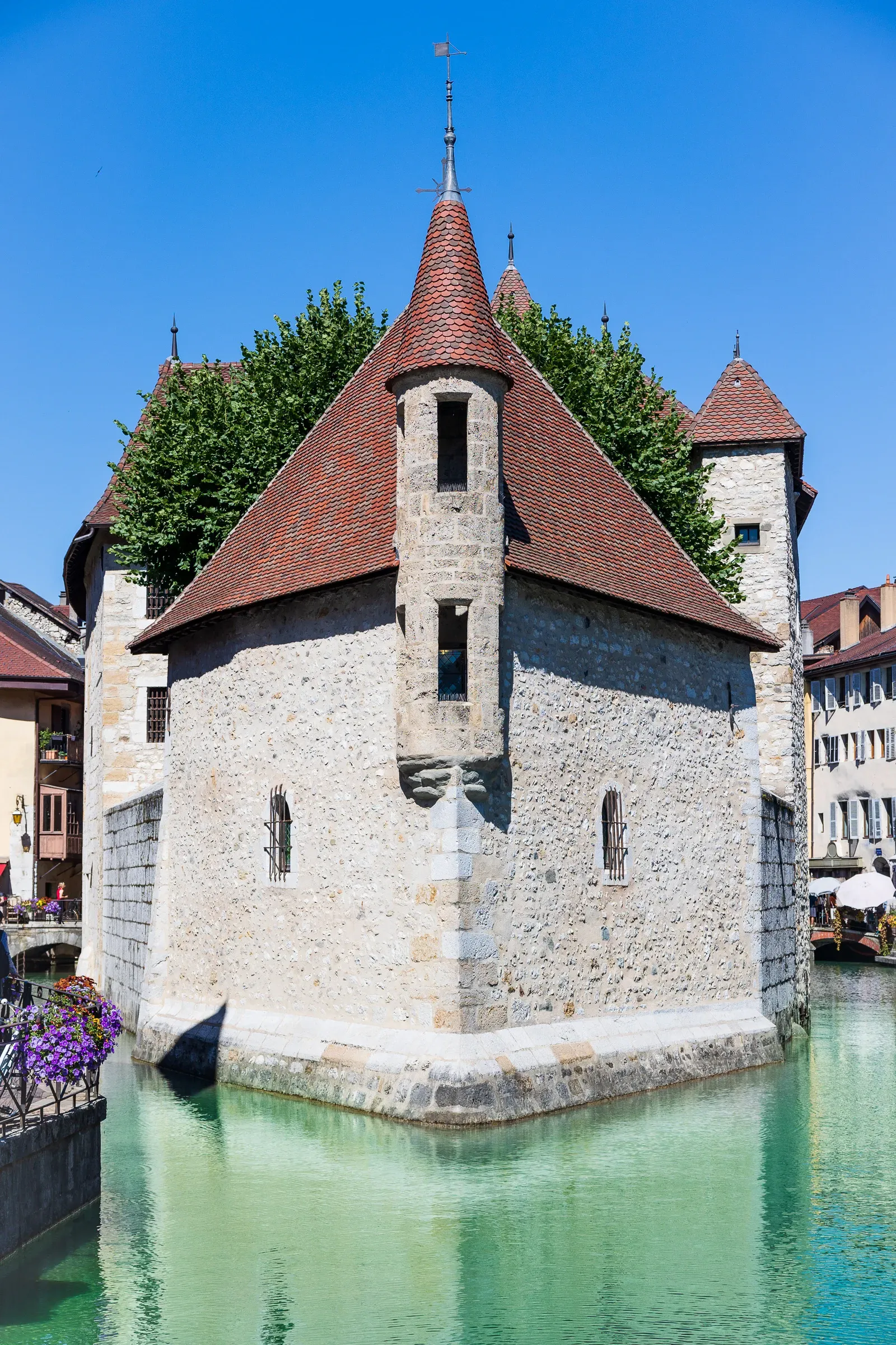 The Palais de l'Isle medieval castle rising from the Thiou canal under a clear blue sky, Annecy