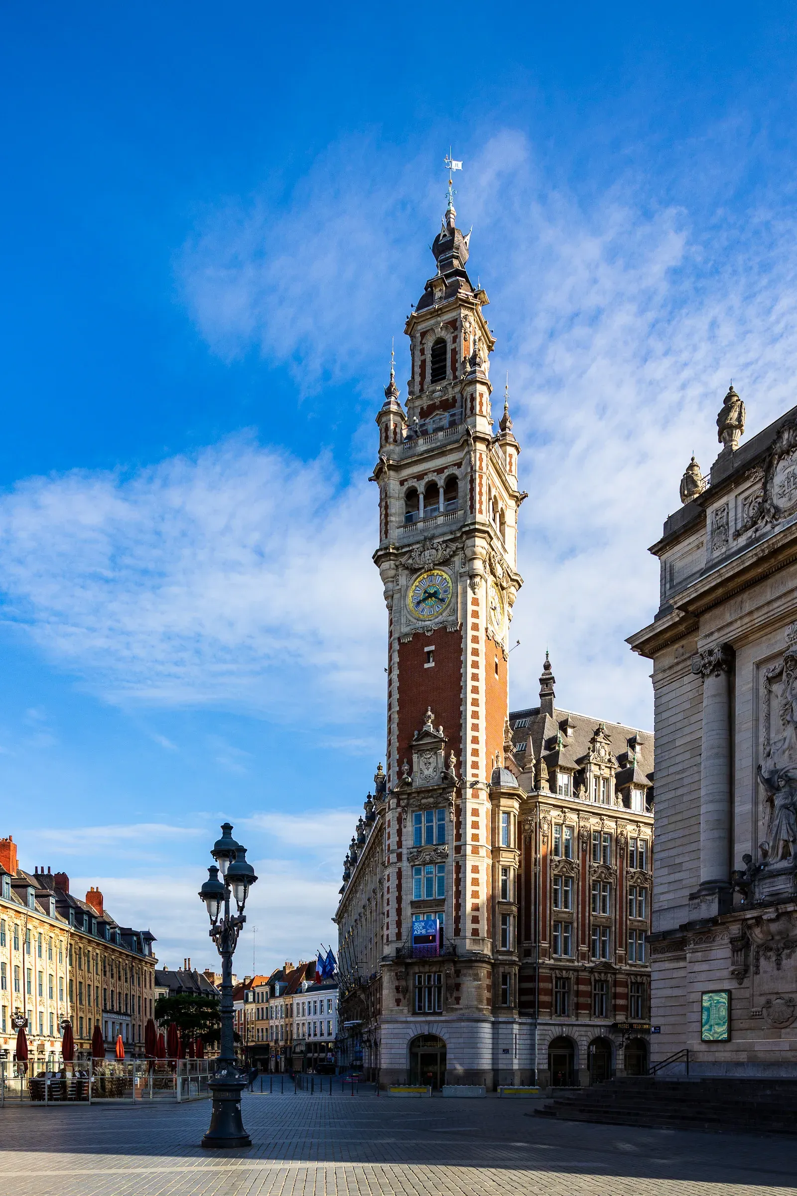 The Chambre de Commerce belfry tower rising above Grand Place under a deep blue sky, Lille