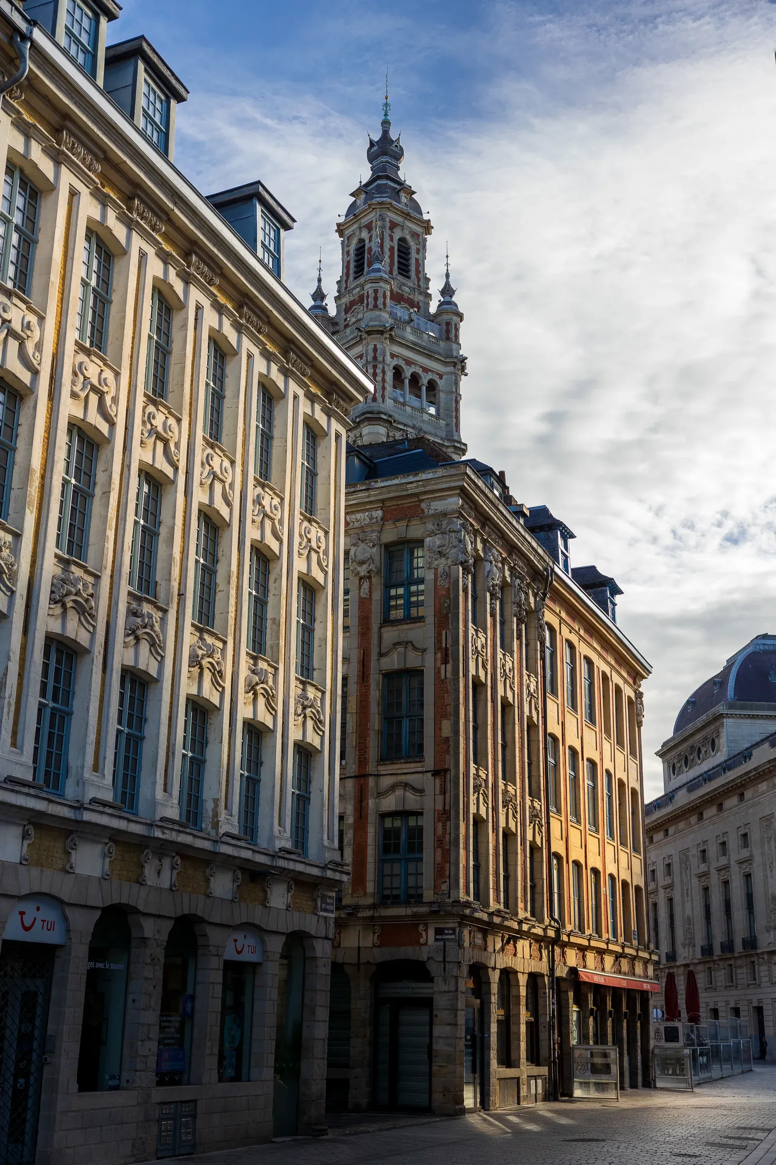 Flemish baroque building facades with the belfry visible above, viewed from a quiet square, Lille