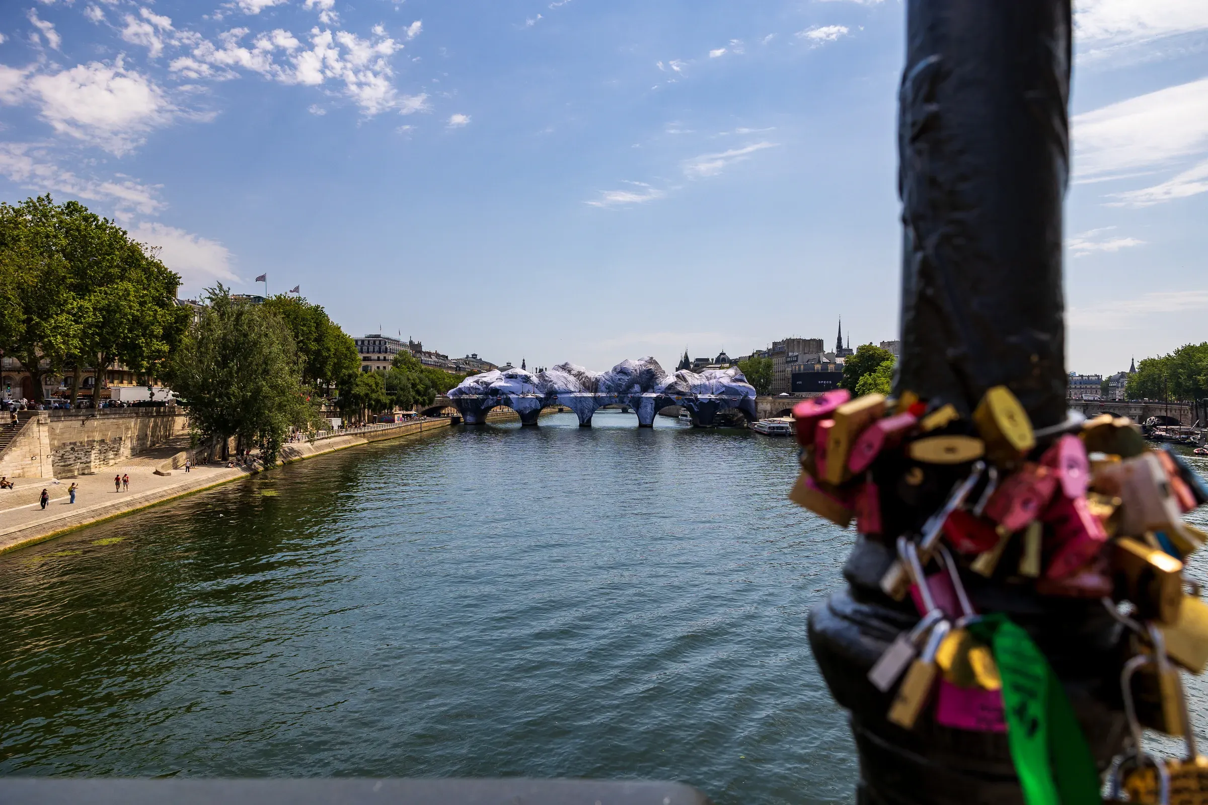 Rows of rubber ducks lined up behind a houseboat window, boats and the Seine reflected in the glass, Paris