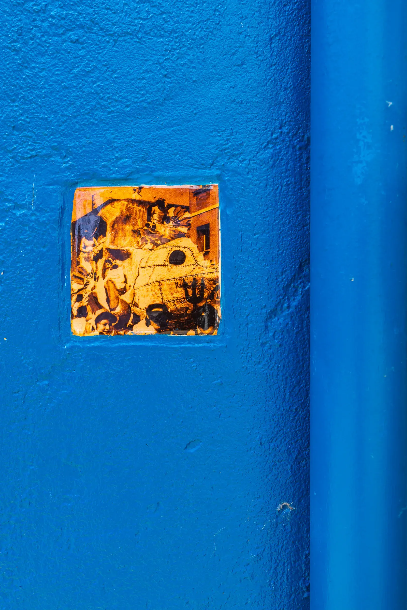 A small square orange comic-book tank illustration embedded as a tile in a blue rendered wall, Trentemoult