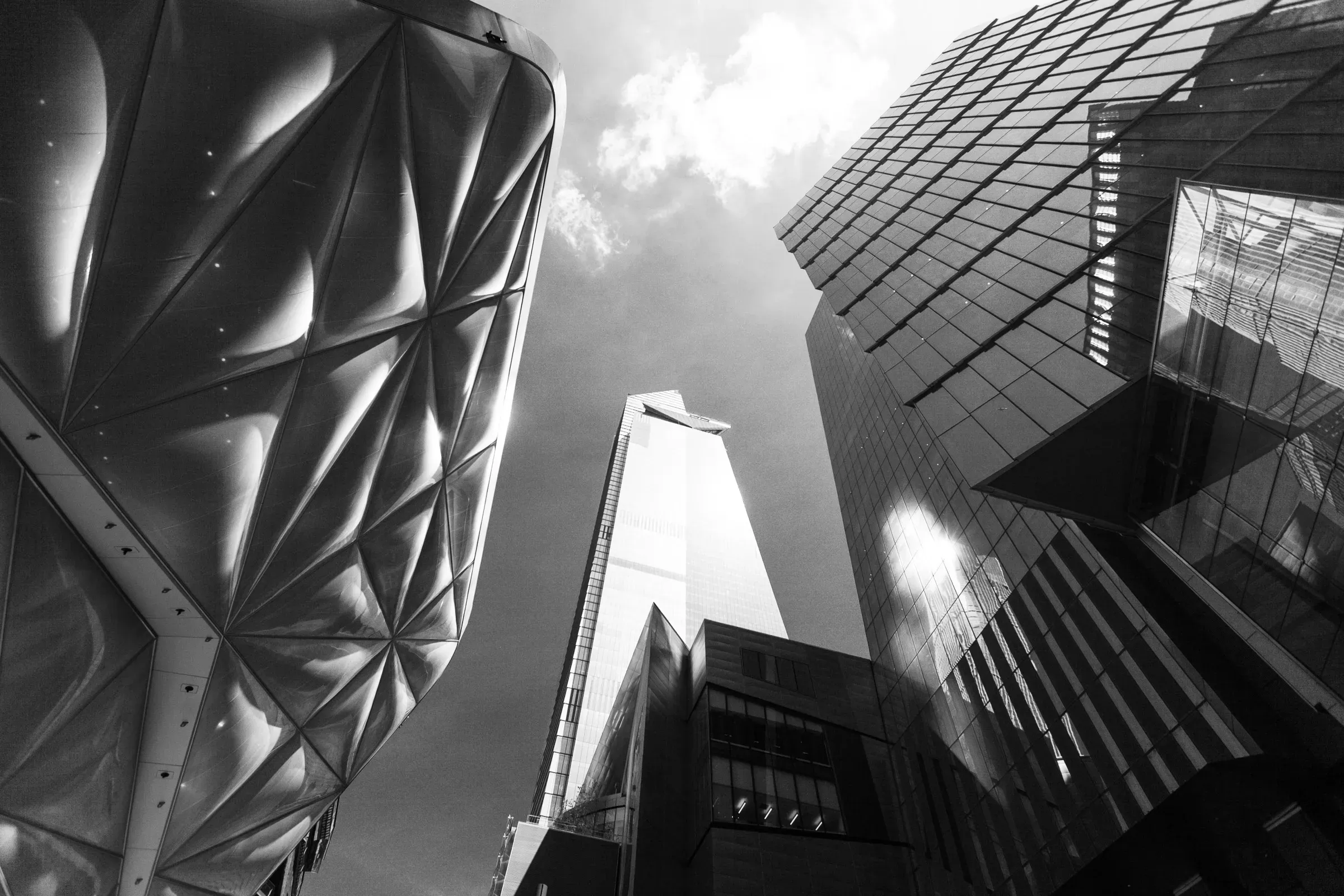 Three contrasting London skyscrapers seen from street level: a faceted metallic tower on the left, a sharp glass point in the centre, a reflective curtain wall on the right