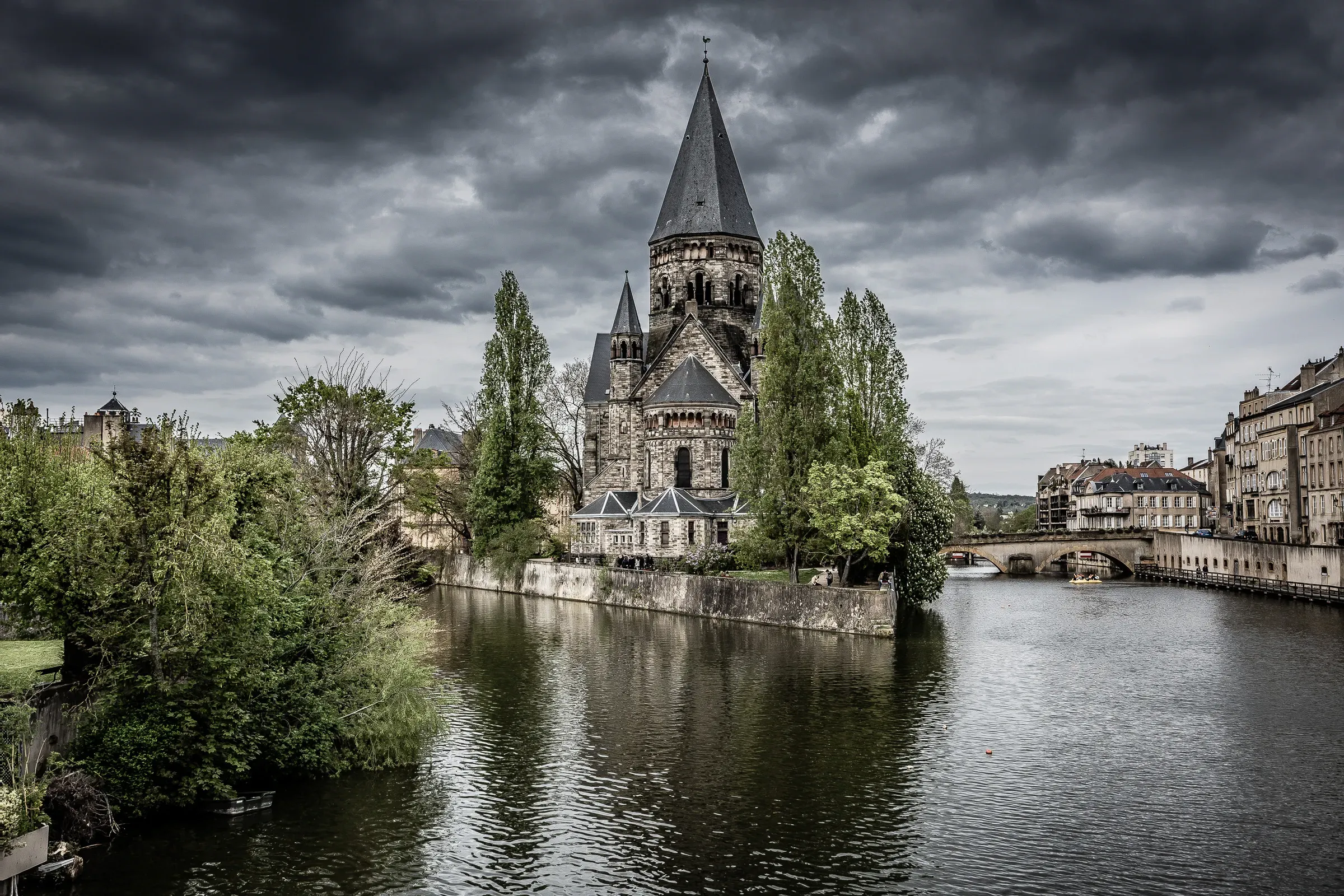 Temple Neuf on its island in the Moselle river under heavy storm clouds, Metz